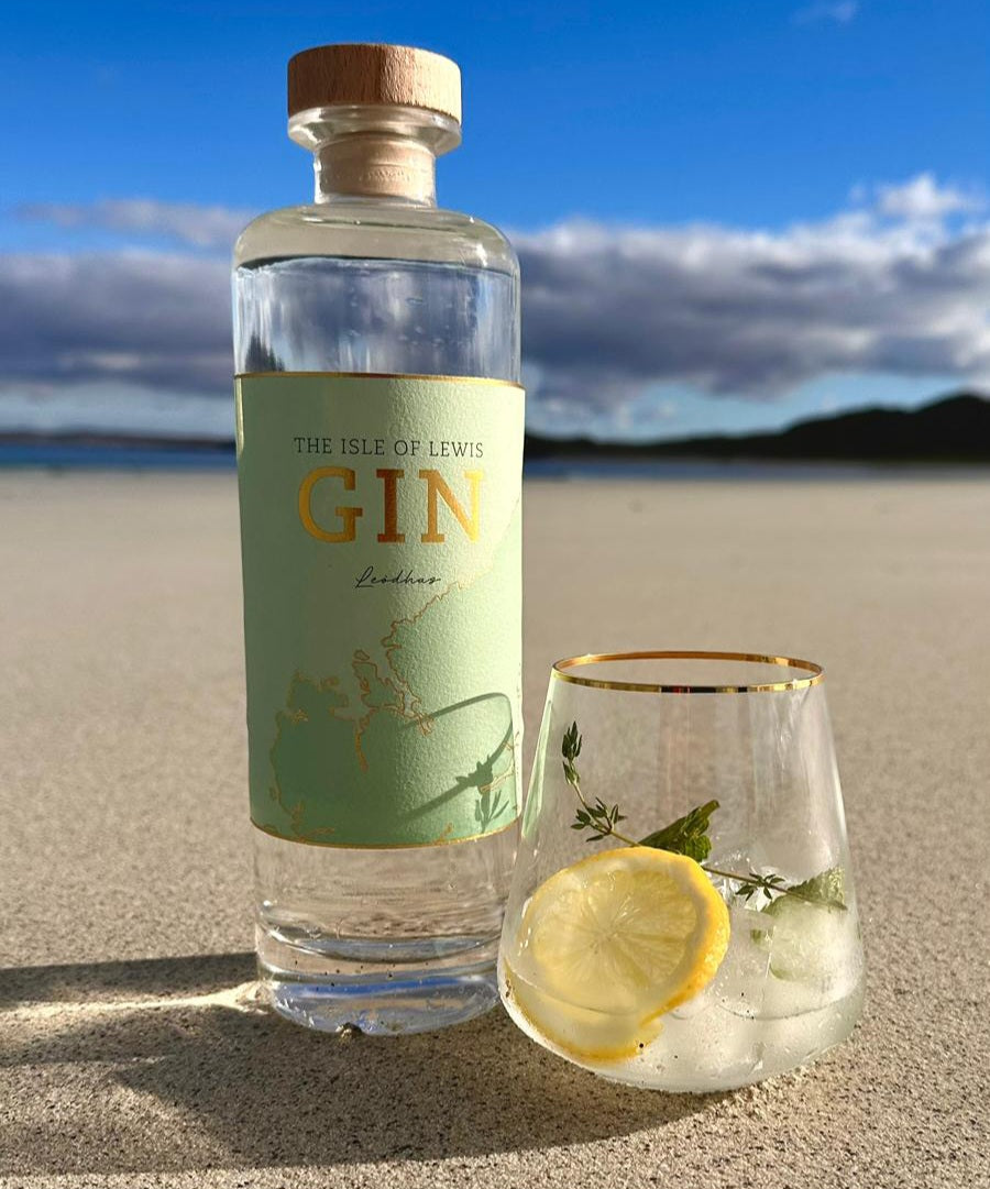 Lewis gin bottle on the beach, chilled measure served with a slice of lemon and thyme
